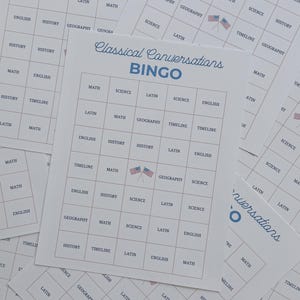 Puede incluir: Una pila de tarjetas de bingo de papel blanco tituladas Classical Conversations BINGO en texto azul. Cada tarjeta presenta una cuadrícula de cinco por cinco llena de materias académicas como Math, Science, Latin, History, English, Geography y Timeline, con un pequeño icono de bandera estadounidense en la casilla central.