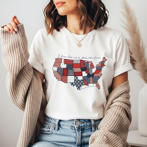 May include: White t-shirt featuring a patchwork design of the United States map in red, white, and blue. The shirt includes the text "To Know God and to Make Him Known" and "Classical Conversations".