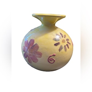 May include: A yellow ceramic vase with a bulbous body and a flared rim. The vase is decorated with hand-painted pink and purple flowers and swirls. This decorative vase is perfect for displaying flowers or as a decorative accent.