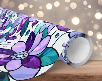 May include: A roll of decorative wrapping paper featuring a floral design in shades of purple, teal, and white. The pattern resembles stained glass, with a large flower motif. The paper is rolled up on a wooden surface.