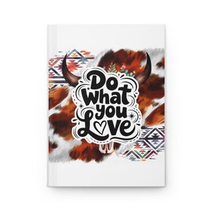 May include: White journal with a cowhide design and the text "Do What You Love". The cover features a stylized cow skull with horns, floral accents, and geometric patterns in shades of brown, orange, and blue.