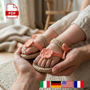 May include: Handmade crochet baby sandals in beige and coral. The sandals feature a flower design on the straps and are held in someone's hands. The PDF icon is in the top left corner.
