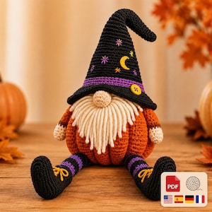May include: A crocheted gnome figure with a pumpkin-shaped orange body, a long cream-coloured yarn beard, and a tall black pointed hat featuring a purple band, a yellow button, and embroidered yellow moon and colourful star motifs.