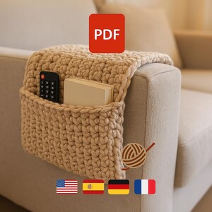 May include: A beige, hand-crocheted sofa arm organizer with a pocket, holding a remote control and a book. The organizer is draped over the arm of a light-colored sofa. A red square with the word "PDF" is in the upper right corner.