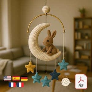 May include: A handmade crochet baby mobile featuring a cream-colored crescent moon, a brown bunny, and hanging star accents in shades of blue and yellow. The mobile is suspended from a gold-colored ring.