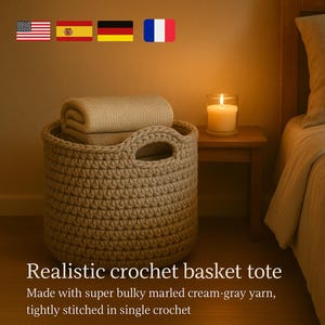 Puede incluir: Un bolso tote de cesta de ganchillo beige con asas, lleno de mantas dobladas. La cesta está hecha con hilo crema-gris jaspeado voluminoso y cosido firmemente. Una vela encendida está sobre una mesita de madera.