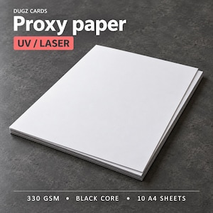 Puede incluir: Una pila de papel blanco DUGZ CARDS Proxy para impresión UV y láser. El producto cuenta con un núcleo negro, un gramaje de 330 GSM e incluye 10 hojas A4. El papel se presenta como una pila rectangular con bordes limpios y superficie lisa.