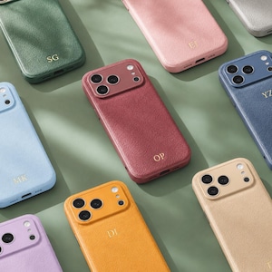 Pode incluir: Uma coleção de capas para smartphone em várias cores, incluindo verde, rosa, azul, vermelho, amarelo, lavanda e bege. Cada capa apresenta uma superfície texturizada, um recorte para a câmara e iniciais douradas como SG, EI, YZ, MK, OP, DI e TR.