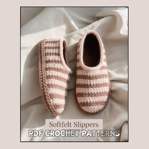 Può includere: Due pantofole in feltro morbido fatte a mano con un motivo a righe nei toni del beige e del marrone. Le pantofole sono esposte su uno sfondo di tessuto chiaro. Il testo "Softfelt Slippers" e "PDF CROCHET PATTERNS" è visibile.