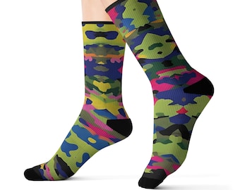 May include: A pair of crew socks with a colorful camouflage pattern. The socks feature a mix of green, blue, pink, and yellow hues. The toe and heel are black, and the cuff is black with a pink border.