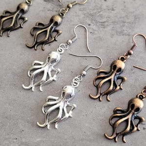 Peut inclure: Un ensemble de quatre boucles d'oreilles en forme de pieuvre, deux argentées et deux en bronze. Les boucles d'oreilles sont de style pendantes avec une fermeture à crochet.