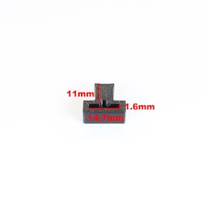 May include: A small, black, T-shaped plastic component. The component measures 14.7mm wide, 11mm high, and 1.6mm thick. The component is set against a white background.