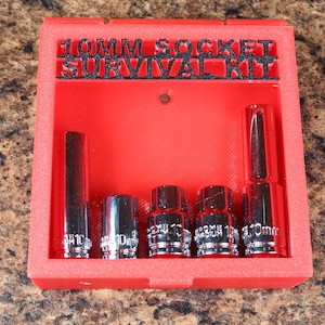 May include: A red plastic case labelled "10MM SOCKET SURVIVAL KIT" contains several chrome sockets. The sockets are of varying lengths and shapes, all designed for a 10mm bolt. The case is rectangular and sits on a brown surface.