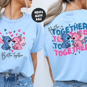 A woman wearing a light blue t-shirt with a graphic design featuring two cartoon characters, one pink and one blue, along with the text "Better Together" and "Together".