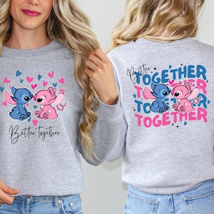 two women wearing gray sweatshirts with a cartoon character design and text on the back.