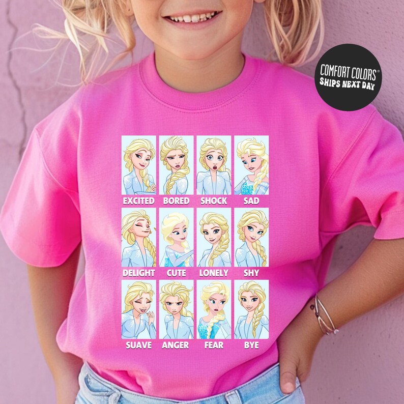 A young girl wearing a pink t-shirt with a collage of twelve different expressions of the Disney character Elsa, each labeled with a different emotion.