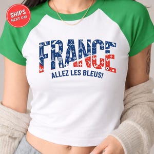 A white t-shirt with the word "FRANCE" printed in large letters, along with the phrase "ALLEZ LES BLUES!" below it.