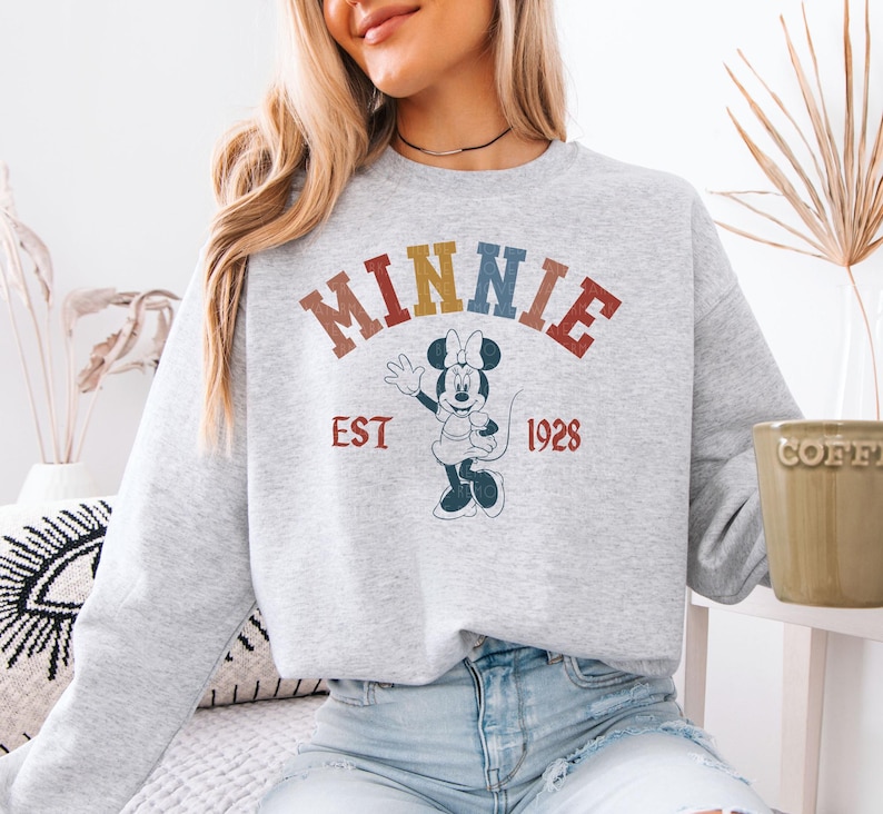a woman sitting on a couch wearing a minnie mouse sweatshirt
