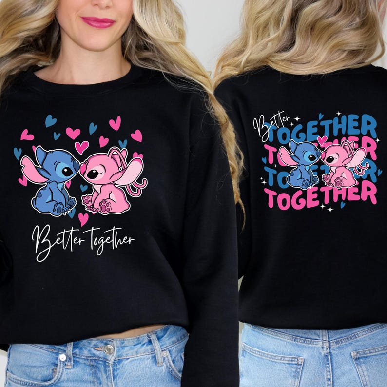 A woman wearing a black sweatshirt with a graphic design featuring two cartoon characters, one pink and one blue, along with the text "Better together" and hearts.