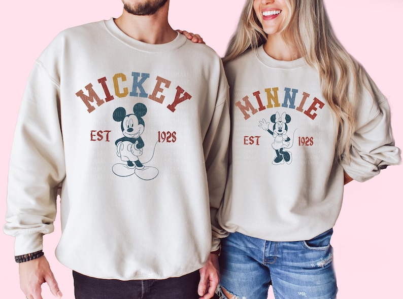 a man and a woman wearing mickey mouse sweatshirts