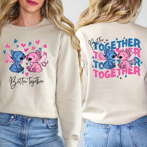two women wearing matching sweaters with a design of two cartoon characters, one pink and one blue, along with the text "Better Together" and "Together".