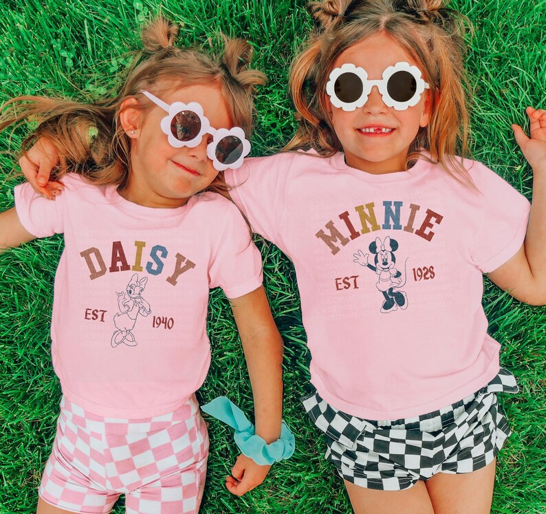 two little girls laying in the grass wearing matching shirts