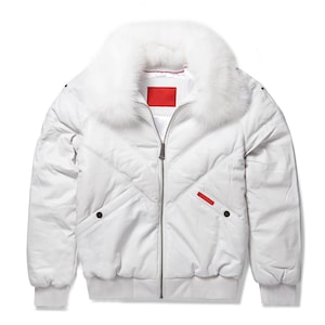 Könnte beinhalten: Weiße Bomberjacke mit flauschigem weißem Pelzkragen. Die Jacke hat ein gestepptes Design, einen Reißverschluss und gerippte Bündchen und Saum. Verfügt über einen roten Akzent am Ärmel.
