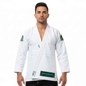 May include: White Jiu-Jitsu uniform with green and black logos on the sleeves and lower front. The uniform has a V-neck design and a white belt. The brand name is displayed on the lower front of the uniform.