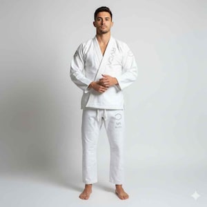 May include: A white martial arts uniform, comprising a jacket and trousers. The jacket displays the brand name "RVCA" on the chest and sleeve. The trousers also feature the brand name on the left leg. The uniform is made of a robust fabric.