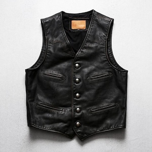 May include: A black leather vest with a V-neck and a button-up front. The vest has two front pockets and decorative stitching along the shoulders and chest. The vest has a small, rectangular patch on the back.