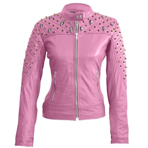 Könnte beinhalten: Eine rosa Lederjacke mit einem gesteppten Schulterdesign und einem silbernen Reißverschluss. Die Jacke hat goldfarbene Spikes und Totenkopfnieten auf den Schultern. Sie hat einen runden Kragen und zwei Reißverschlusstaschen.