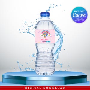 May include: A clear plastic water bottle with a blue cap and a custom pink label featuring a rainbow, cartoon characters, and the text "HI FRIENDS! CAN YOU SAY... RACHEL is turning ONE!" surrounded by a dynamic splash of water droplets.