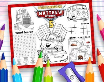 Op de afbeelding: Een rechthoekig verjaardagsactiviteitenblad met Cars-personages, een woordzoeker, een boter-kaas-en-eieren-raster en een doolhof. De tekst luidt READY STEADY GO! MATTHEW IS TURNING 5. Het blad is omringd door kleurpotloden en een puntenslijper.