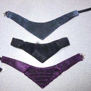 Könnte beinhalten: Drei glitzernde Halsbänder in verschiedenen Farben: Blau, Schwarz und Lila. Jedes Halsband hat einen Verschluss und ist aus einem weichen, dehnbaren Material gefertigt.