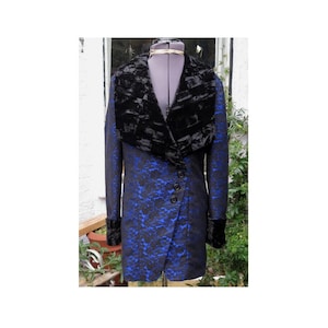 May include: A long, blue and black floral patterned coat with a black faux fur collar and cuffs. The coat has a unique asymmetrical button closure and is displayed on a mannequin.