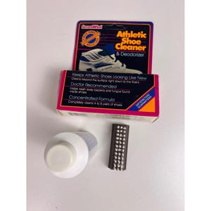 Op de afbeelding: Een atletische schoenreiniger en deodorant kit. De kit bevat een flesje reiniger, een borstel en een doos met productinformatie. Op de doos staat "Keeps Athletic Shoes Looking Like New" en "Doctor Recommended."
