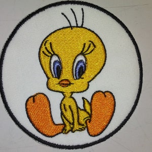 May include: Embroidered patch featuring the cartoon character Tweety Bird. The yellow bird with blue eyes and orange feet is centered on a white circular background with a black border. The patch is likely for clothing or accessories.