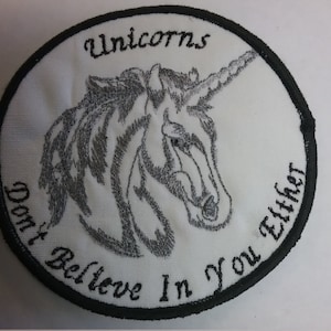 May include: White embroidered patch with a black border. The patch features a silver unicorn head with the text "Unicorns Don't Believe In You Either".