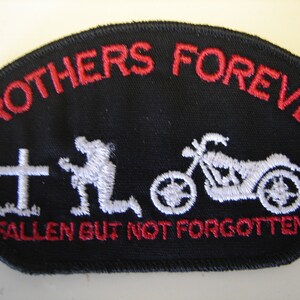 May include: Black patch with red embroidered text reading "BROTHERS FOREVER" and "FALLEN BUT NOT FORGOTTEN." Features a white embroidered cross, a kneeling figure, and a motorcycle. The patch has a curved top edge.