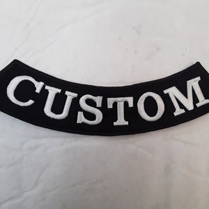 May include: Black motorcycle patch with white embroidered text that reads "CUSTOM".