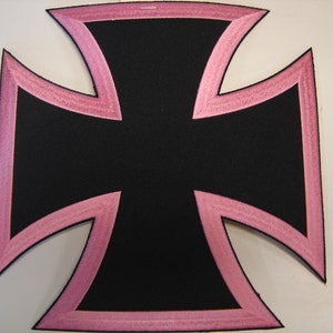 May include: Black iron cross patch with a pink outline. The patch is made of fabric and has a stitched edge.
