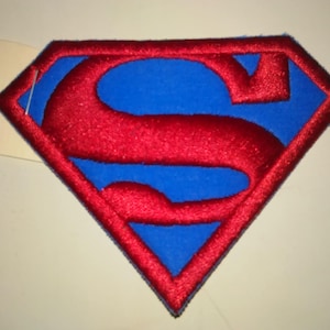 May include: Red and blue embroidered Superman logo patch. The logo is a red letter "S" on a blue background, with a red diamond shape around it.