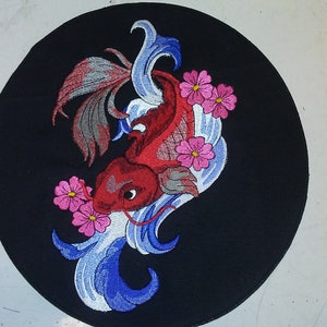 May include: A red and silver koi fish with blue and white waves and pink flowers embroidered on a black circular patch.