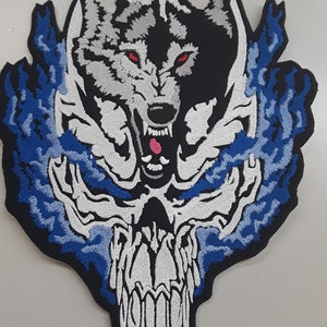 May include: Embroidered patch featuring a white and gray wolf with red eyes snarling, surrounded by blue flames and a white skull with teeth.