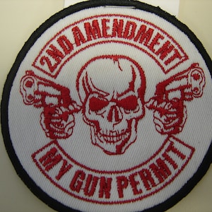 May include: A white embroidered patch with a red skull and crossbones design. The text "2nd Amendment My Gun Permit" is written in a red circular banner around the skull and crossbones.