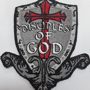 May include: A gray embroidered patch with a red cross and the words "Disciples of God" in white lettering. The patch is shaped like a shield with a decorative flourish at the bottom.