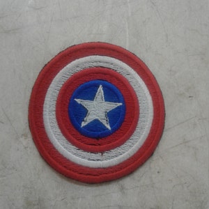 May include: A red, white, and blue embroidered patch with a white star in the center. The patch is circular and has a stitched border.