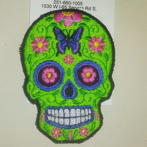 May include: Green embroidered sugar skull patch with pink and purple flowers and a blue butterfly.