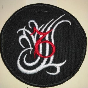 May include: A black embroidered patch with a white stylized design featuring the number "6" in red.