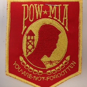 May include: Red and yellow embroidered patch with the words "POW*MIA You Are Not Forgotten".